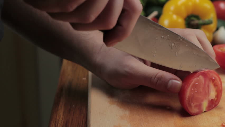 Chef cutting up a tomato with a knife, tracking shot