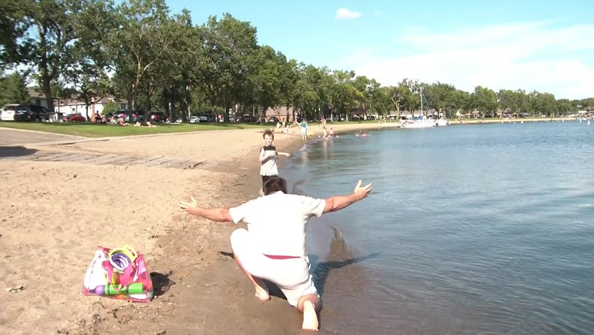 Father and son reunite on the beach with son running up to dad and jumping into his arms, they spin, boy is set down on sand, they walk in sunshine.