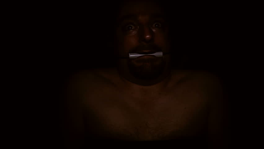 a frightened man strapped to a hospital gurney is pushed down a dimly lit hallway