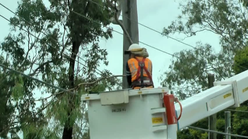 Queensland- Australia circa 2013 Recent floods and wild weather have caused damage and death. Worker clears trees from power lines.