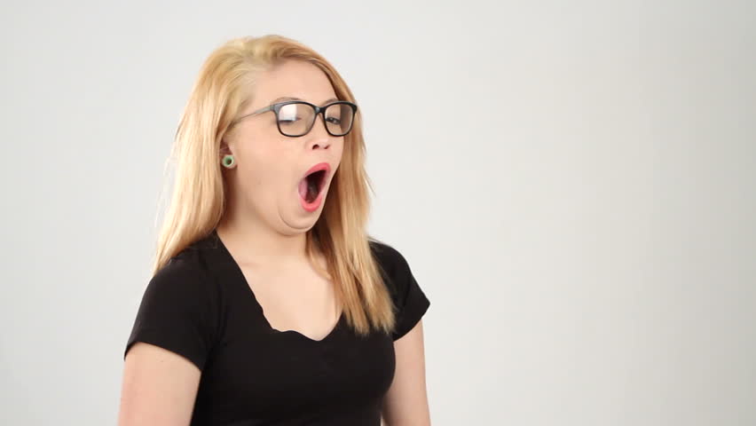Sleepy eyed teenager yawns in front of white background.