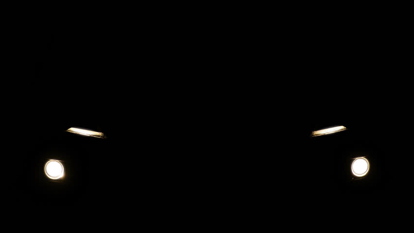 Luminous headlights of automobile contrast with black background. Concept of car presentation. Moving car with lights at night. Stylish and abstract motion with isolated front headlights of auto.
