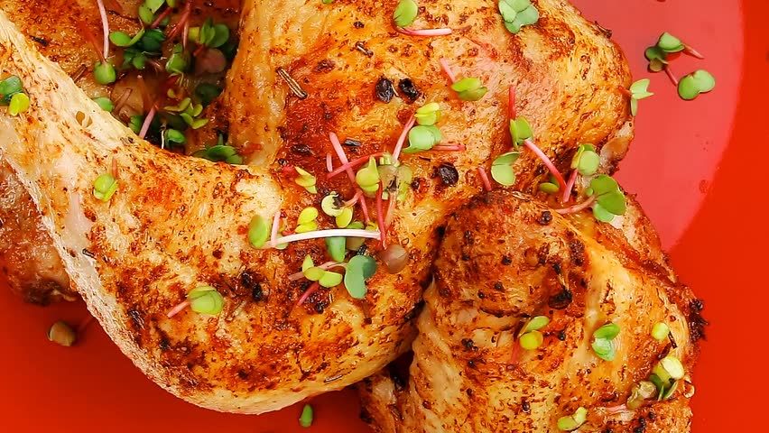 meat food : grilled quarter chicken garnished with green sprouts and red peppers on red plate hidef slow motion intro