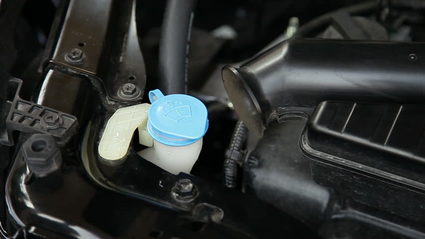 Car servicing mechanic pouring water to injection water bottle for glass, component of car engine