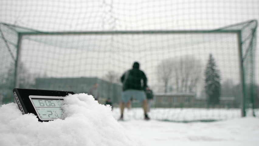 determined soccer players scoring a penalty in winter time thermometer in foreground