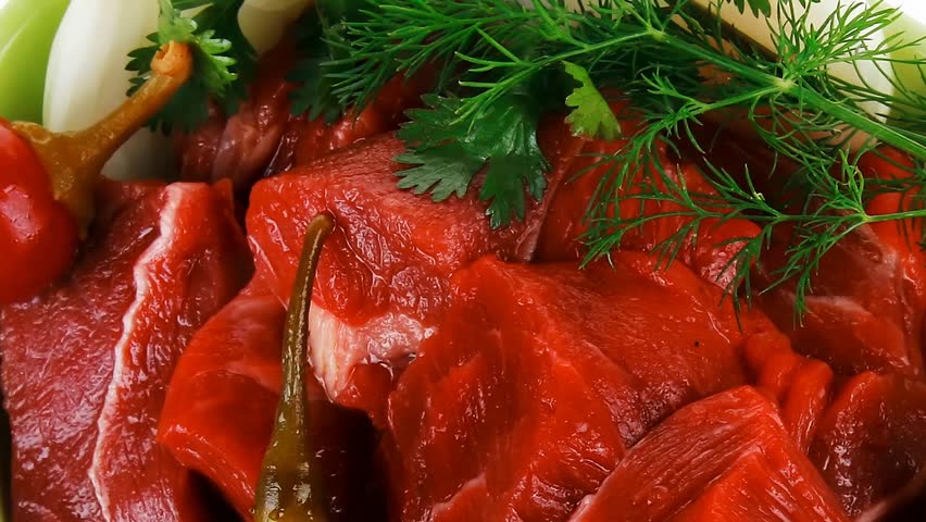 uncooked fresh beef meat chunks on ceramic bowls with vegetables and red peppers hidef slow motion intro