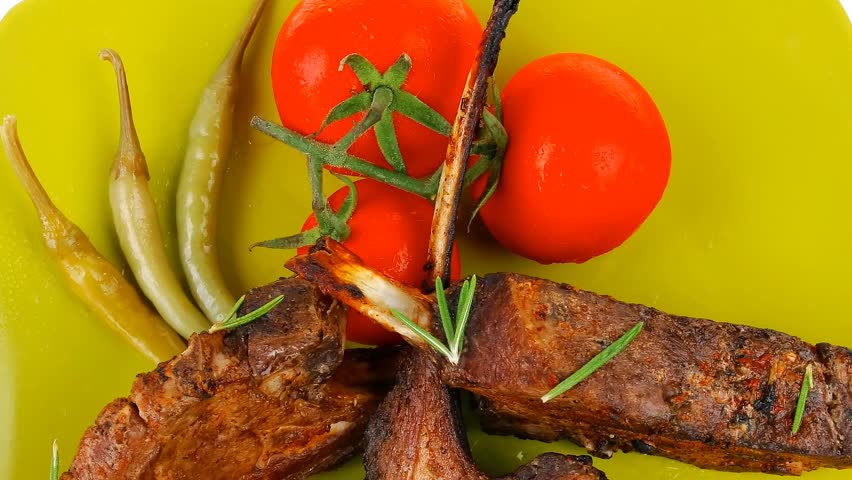 served savory plate: meat ribs with chives and red hot peppers on green