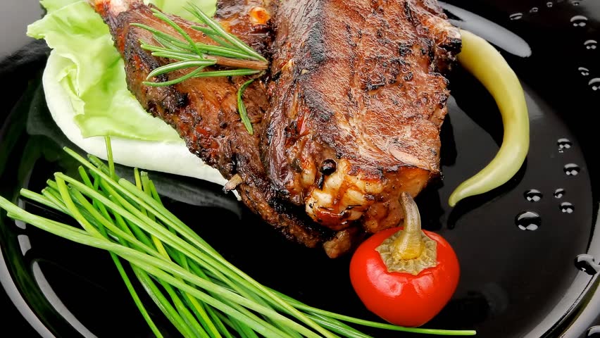 meat savory: roast ribs on black plate with peppers and chives