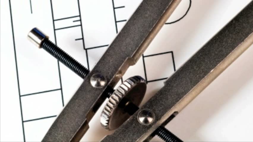 Drafting compass and ruler against a blueprint