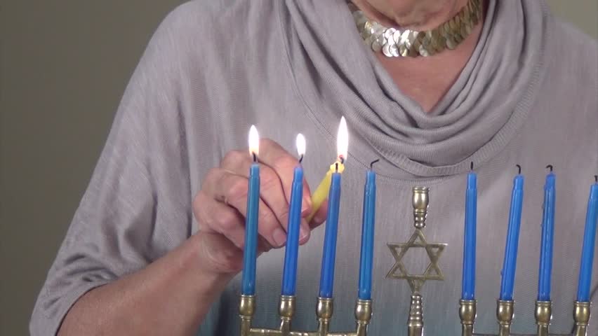 Happy Hannukah. Woman lights the menorah. 
