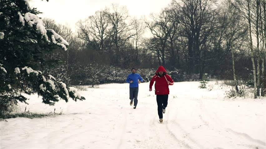 Runners while training in a wintry wood, slow motion shot at 240fps, crane shot
