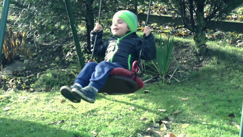 Little boy swinging in autumn park and smiling, slow motion shot at 120fps
