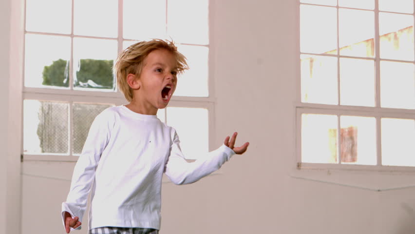 Boy in pajamas jumping and shouting in front of window in slow motion