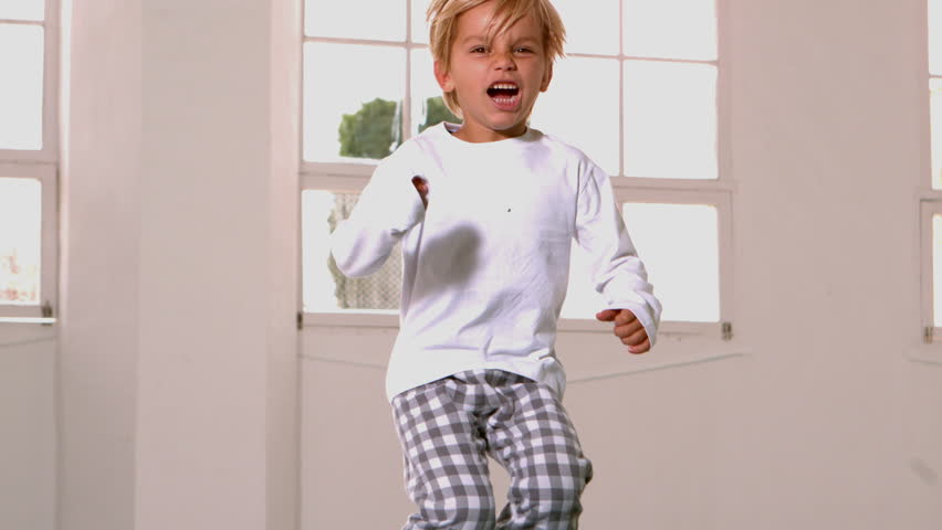 Boy in pajamas jumping and yelling in front of window in slow motion