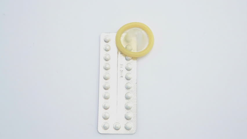 Contraceptive pill with condom on revolving blue surface