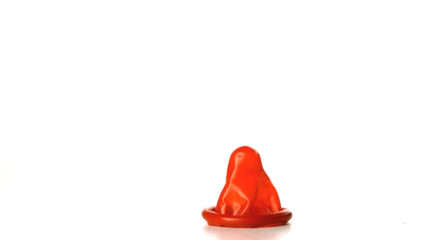 Red condom falling on white background in slow motion