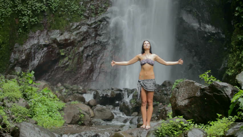 Beautiful woman under waterfall in the tropics