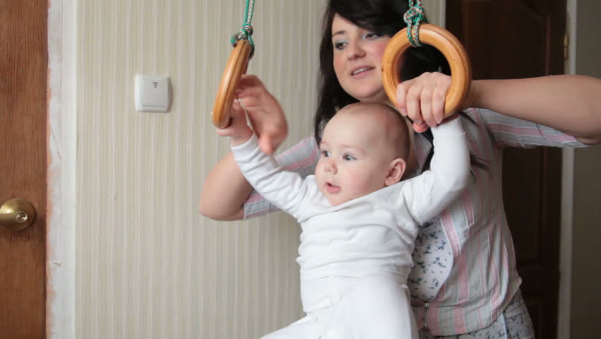 Mother helping baby on gymnastic rings