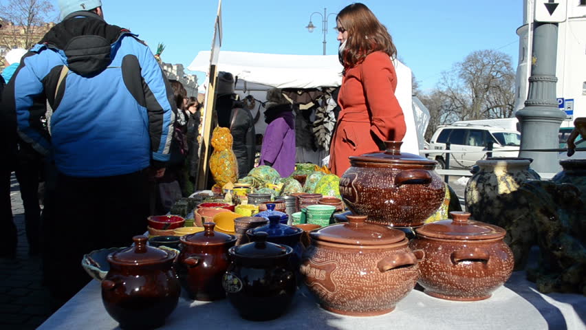 VILNIUS, LITHUANIA - MARCH 02: Young merchant woman sell various handmade crockery clay pots in outdoor crafts market fair on March 02, 2012 in Vilnius.
