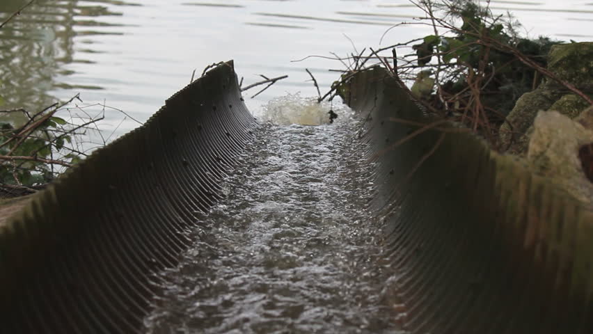 Rainwater funnels through an open culvert and pours into a river/Rainwater in Open Culvert/Rainwater funnels through an open culvert and pours into a river