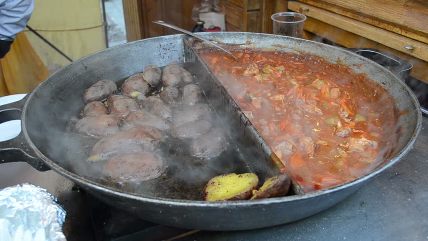 Potatoes meat and vegetable stew bake in huge steel pan in street outdoor restaurant.