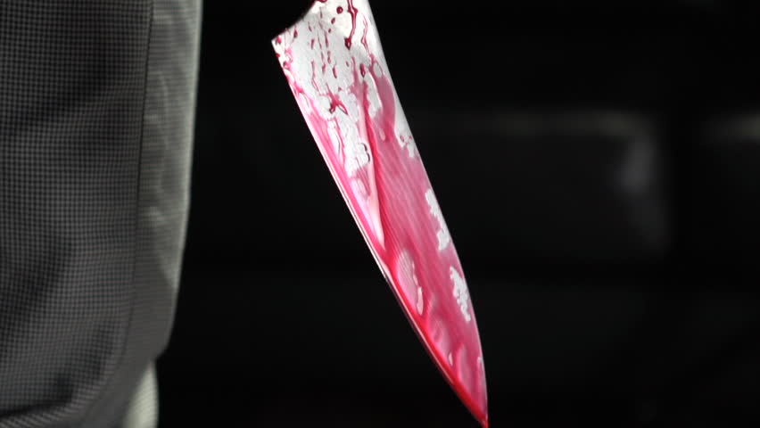 Pan down of murderer holding bloody knife