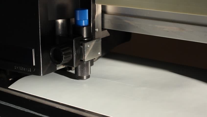 Cutting plotters use knives to cut the letters on gray vinyl film. Three-quarter view close-up
