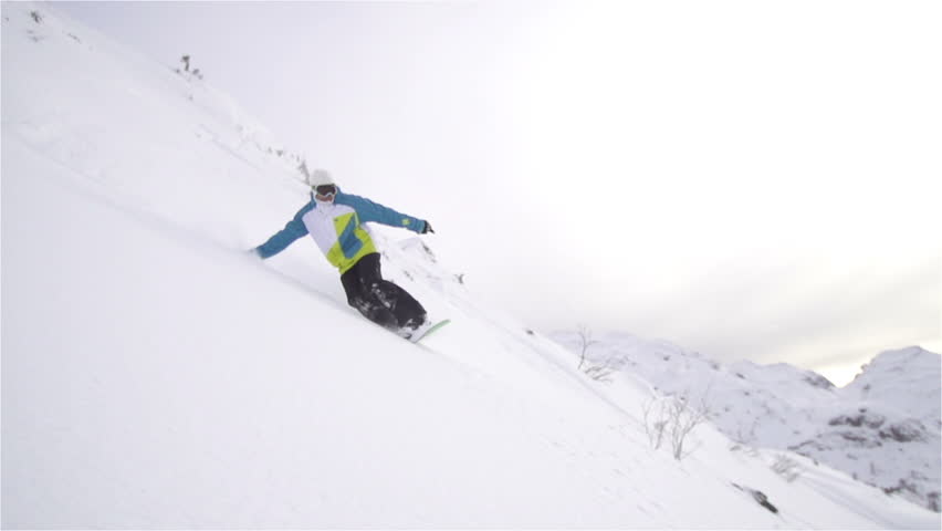 SLOW MOTION: snowboarder carving in fresh snow