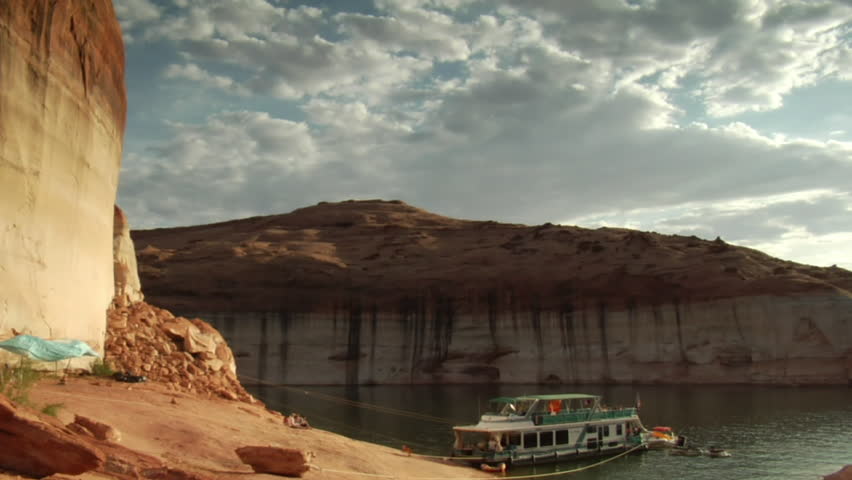 tilt down shot from red rock cliffs to houseboat on Lake Powell