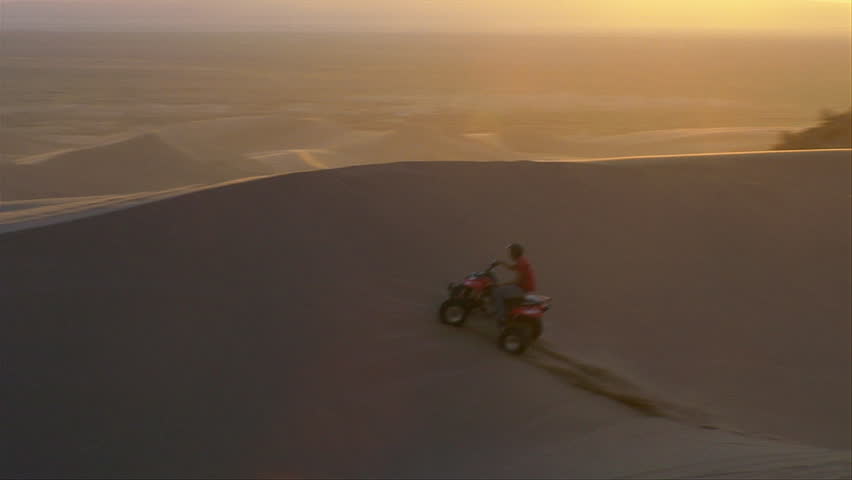 ATV rider on dunes at sunset