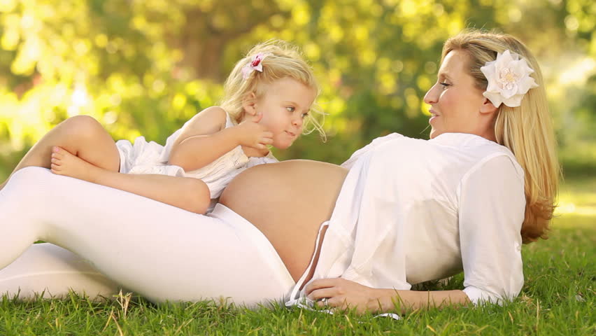 Curious little girl listening to her pregnant mother's belly