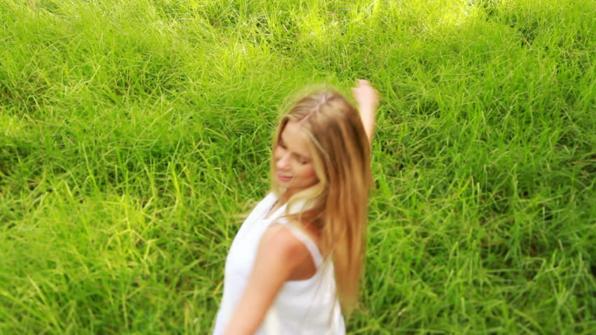Carefree young woman spinning around in nature/garden with arms outstreched