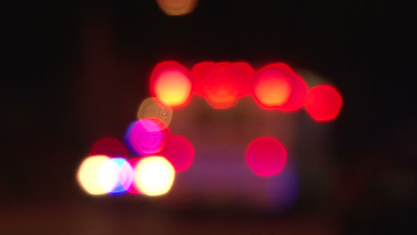PORTLAND OREGON, CIRCA 2013: Police lights flashing from ambulance as it drives away at night, downtown at crime scene, rack focus.