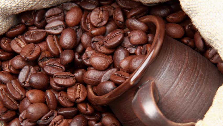 Textured brown ceramic cup full of coffee beans