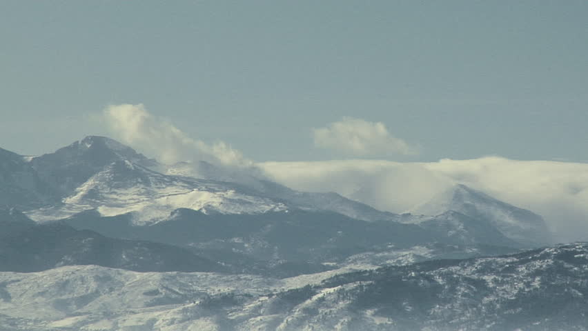 Stormy Peaks. Hurricane force winds lash clouds and snow cover atop Long's Peak in Colorado on mid-winter day.