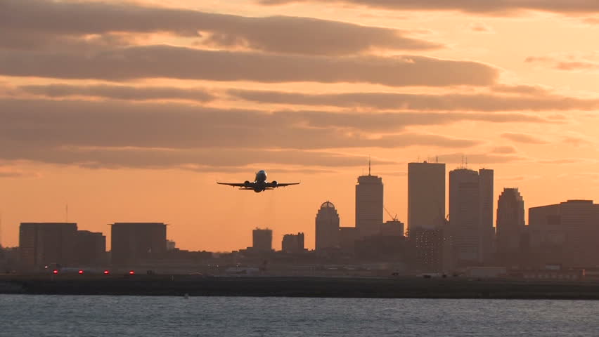 Airplane takeoff from Logan Airport, Boston at sunset camera follows
