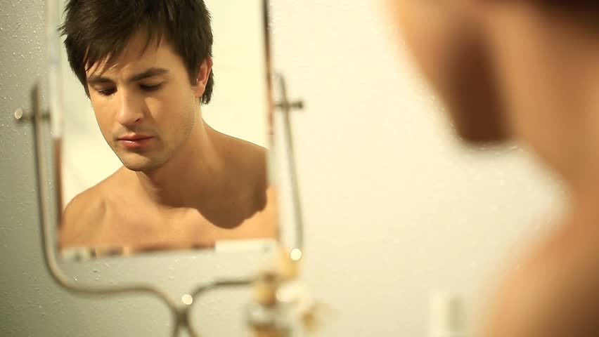 man shaves in front of the mirror