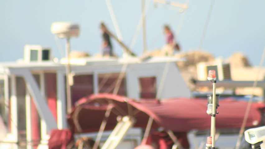 boats anchored at Jaffa port out of focus with two women pass by out of focus
