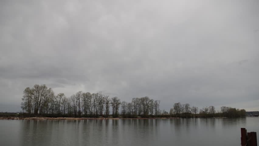 Tug Boat pulling a log boom up the Fraser River on a cloudy day in Vancouver time lapse