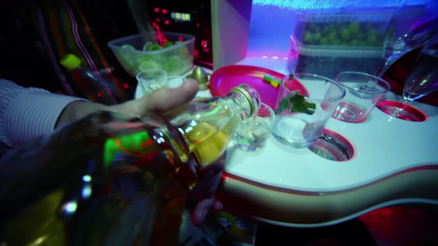 Man pours alcohol in small glasses at table in limo