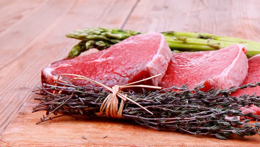 prime fillet meat : dry raw beef on cutting board with asparagus thyme bundle color peppercorn mix and red paprika powder mixed with dry spices over wooden table ready to cooking