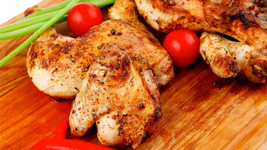 roast meat : chicken legs garnished with green sprouts and peppers on wooden plate isolated over white background