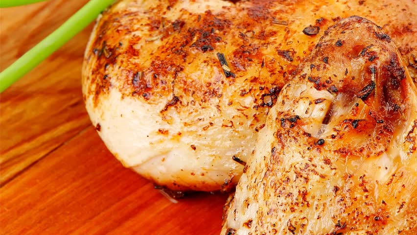 roast meat : chicken legs garnished with green sprouts and peppers on wooden plate isolated over white background