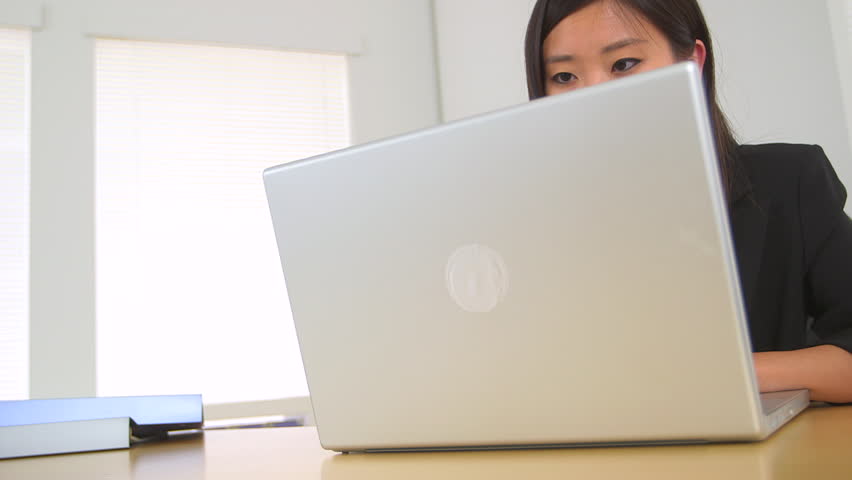 Happy Chinese businesswoman working at desk