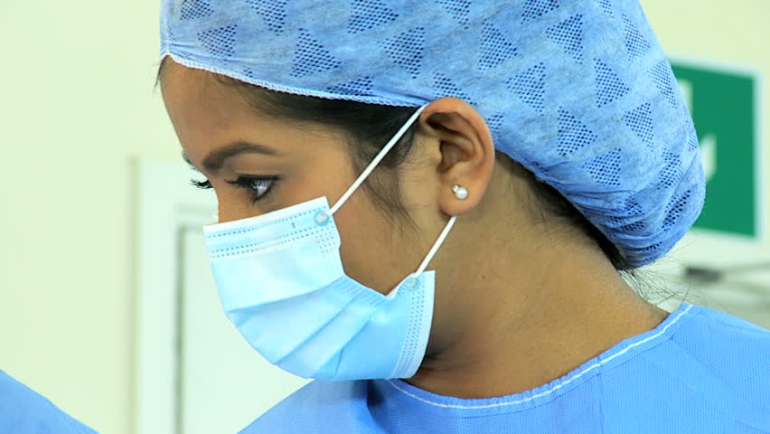 Multi ethnic medical team performing operation in hospital operating theater head and shoulders