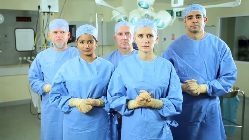Portrait multi ethnic 5 member doctor nursing team wearing surgical scrubs operating room looking to camera