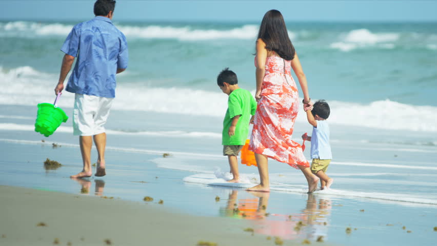 Young Hispanic family walking together on beach shot on RED EPIC