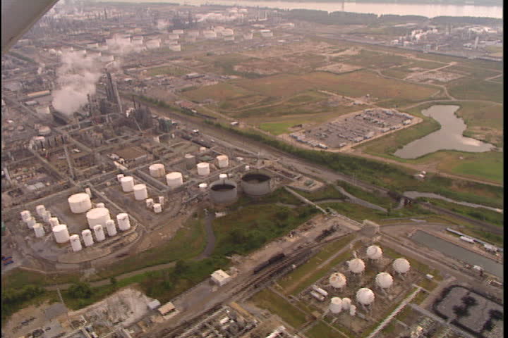 CONVENT, LOUISIANA - CIRCA SEPTEMBER 1999: Aerial shot of many oil storage tanks and smoke spewing from smokestacks at oil refineries.