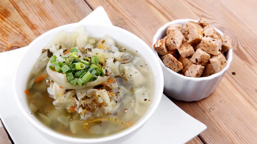 diet food : hot vegetable soup with bread crackers in white bowl on stand over wood table