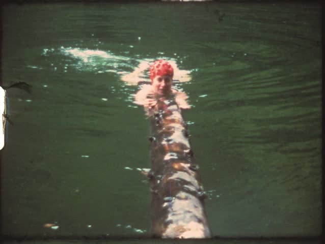 Vintage 8mm film: Woman swimming in sea, with tree log